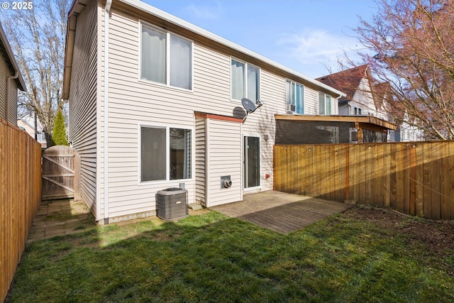 rear view of property with central air condition unit and a yard