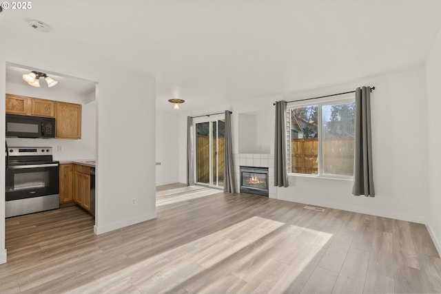 unfurnished living room featuring a tile fireplace and light hardwood / wood-style floors