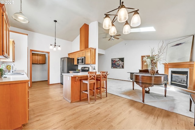 1041 Irving Rd, Eugene, OR 97404 - kitchen with stainless steel appliances, a chandelier, a fireplace, a ceiling fan, and light wood finished floors