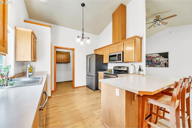 1041 Irving Rd, Eugene, OR 97404 - kitchen with appliances with stainless steel finishes, ceiling fan, a kitchen breakfast bar, a peninsula, and light wood-type flooring