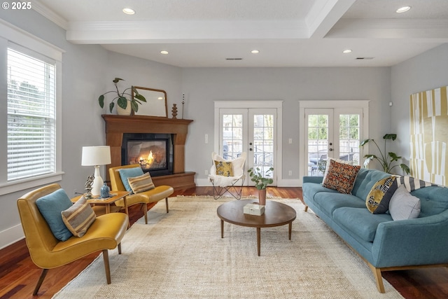 living area featuring plenty of natural light, a glass covered fireplace, wood finished floors, beamed ceiling, and french doors