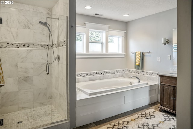 full bath with visible vents, a garden tub, a textured ceiling, vanity, and a shower stall