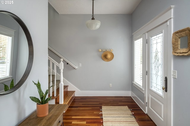 foyer with dark wood-style flooring, a healthy amount of sunlight, stairway, and baseboards