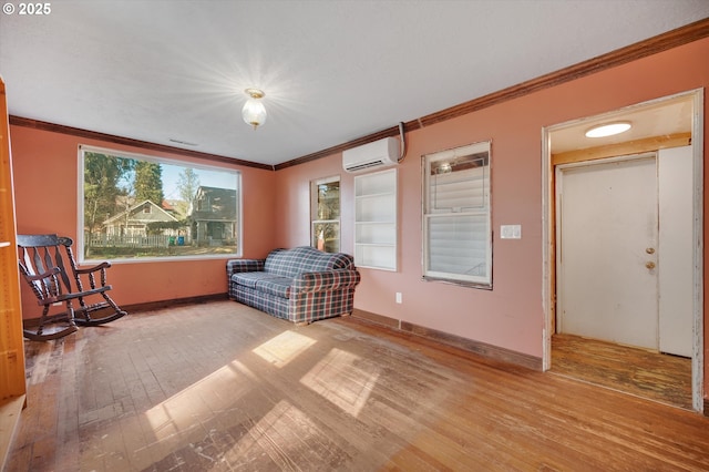 sitting room featuring wood-type flooring, ornamental molding, baseboards, and a wall mounted air conditioner