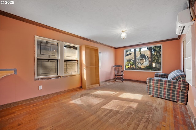 unfurnished room featuring a textured ceiling, baseboards, an AC wall unit, ornamental molding, and hardwood / wood-style floors