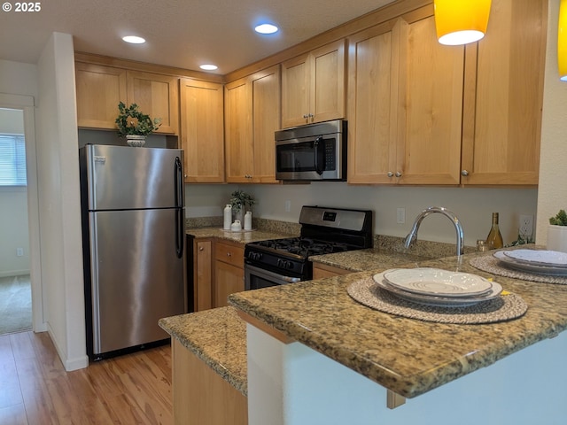 3159 SW Jaden Dr, Beaverton, OR 97003 - kitchen with stainless steel appliances, a peninsula, light wood-style flooring, light stone counters, and recessed lighting