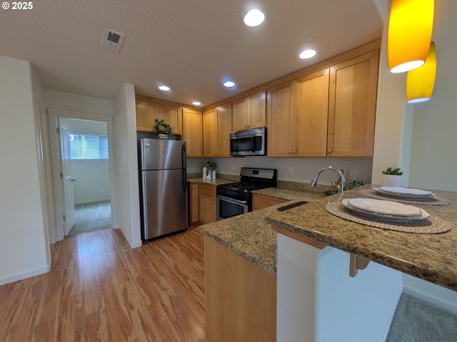 3159 SW Jaden Dr, Beaverton, OR 97003 - kitchen featuring stainless steel appliances, stone counters, a peninsula, light wood-style floors, and recessed lighting