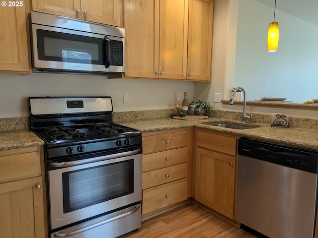 3159 SW Jaden Dr, Beaverton, OR 97003 - kitchen featuring stainless steel appliances, a sink, light wood finished floors, light stone counters, and decorative light fixtures