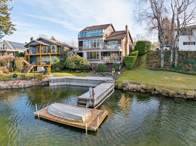 view of dock with a water view and a lawn