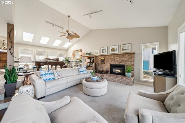 carpeted living room featuring a brick fireplace, rail lighting, vaulted ceiling, and ceiling fan