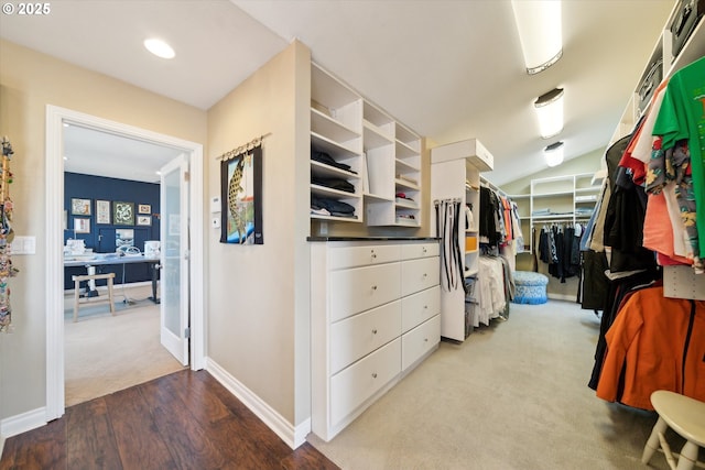 walk in closet with lofted ceiling, carpet flooring, and wood finished floors