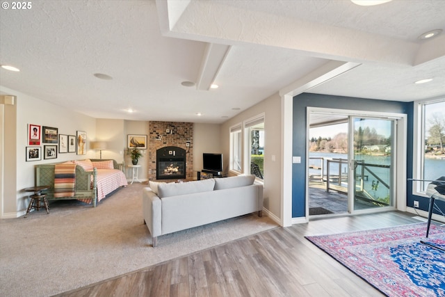 living area with a textured ceiling, a fireplace, wood finished floors, and baseboards