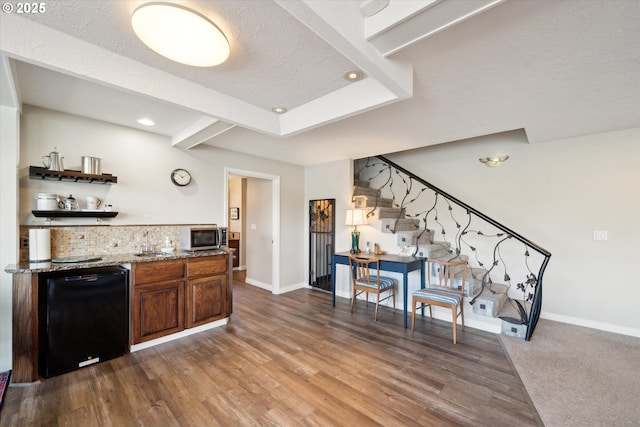 interior space with wood finished floors, decorative backsplash, light stone countertops, dishwasher, and stainless steel microwave