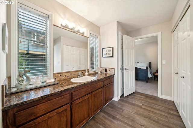 bathroom with decorative backsplash, wood finished floors, vanity, and baseboards