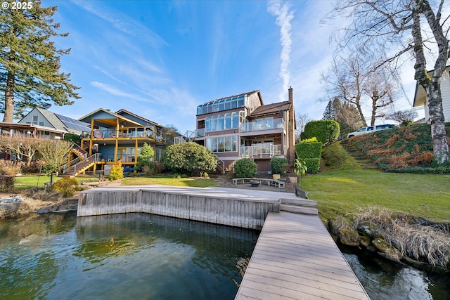 rear view of house with a water view and a yard