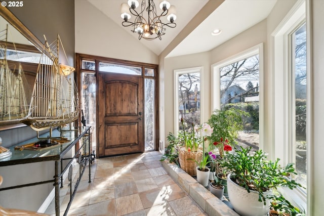 entryway featuring lofted ceiling, stone finish floor, recessed lighting, and an inviting chandelier