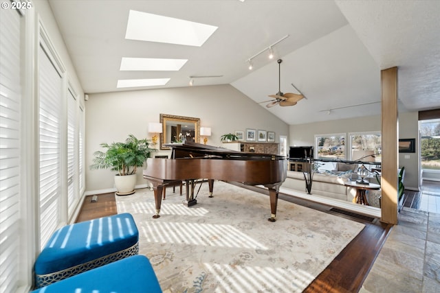 sitting room featuring baseboards, lofted ceiling with skylight, ceiling fan, wood finished floors, and rail lighting