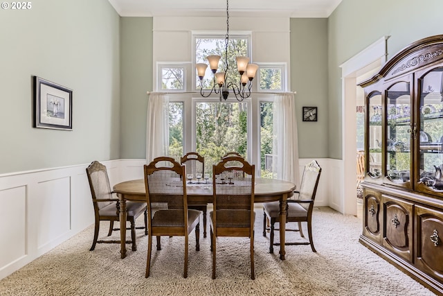 31235 SW Willamette Way, Wilsonville, OR 97070 - dining space with a chandelier, a decorative wall, a wainscoted wall, light carpet, and a towering ceiling