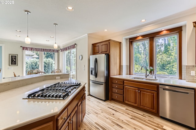 31235 SW Willamette Way, Wilsonville, OR 97070 - kitchen with stainless steel appliances, a sink, light wood finished floors, brown cabinetry, and crown molding
