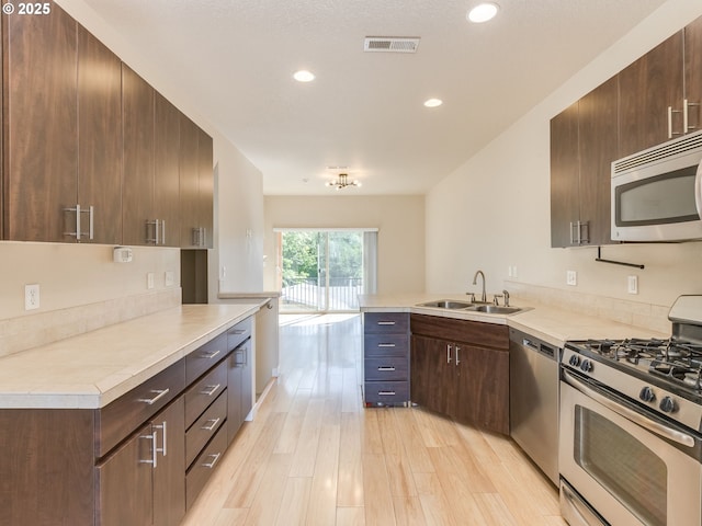 10442 SW Akilean Ter, Portland, OR 97223 - kitchen with appliances with stainless steel finishes, a sink, light countertops, a peninsula, and light wood finished floors