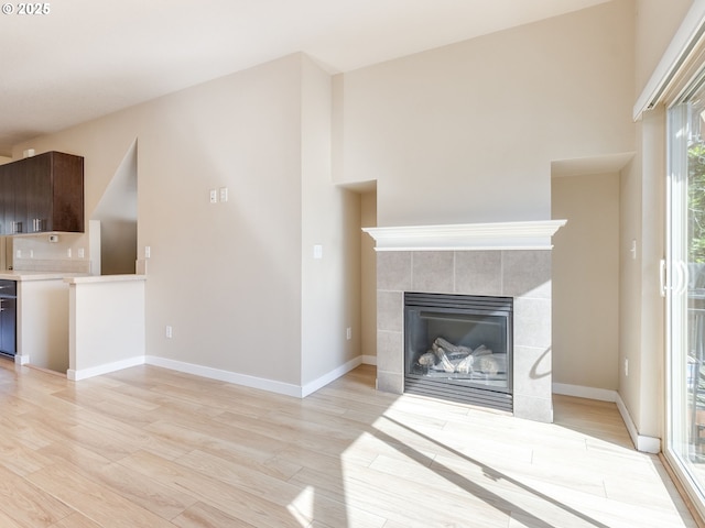 10442 SW Akilean Ter, Portland, OR 97223 - unfurnished living room with light wood finished floors, a tiled fireplace, and baseboards