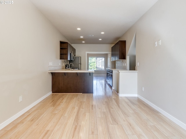 10442 SW Akilean Ter, Portland, OR 97223 - kitchen featuring open shelves, a peninsula, light countertops, light wood-style flooring, and recessed lighting