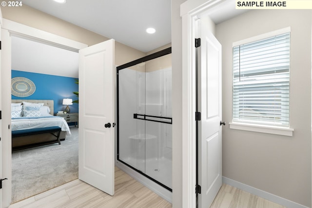 bathroom featuring recessed lighting, baseboards, a shower stall, and ensuite bath