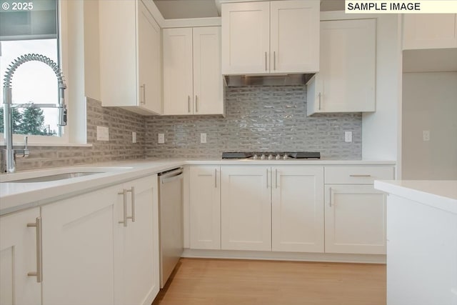 kitchen featuring light countertops, backsplash, appliances with stainless steel finishes, white cabinetry, and a sink