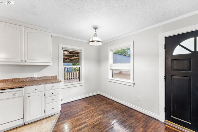 unfurnished dining area with a textured ceiling, ornamental molding, baseboards, and light wood-style floors