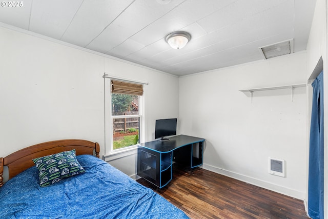 bedroom featuring baseboards, ornamental molding, wood finished floors, and attic access