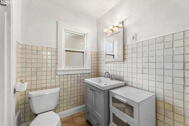 bathroom with tile walls, tile patterned flooring, vanity, and toilet