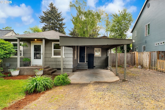 single story home featuring a fenced backyard, a carport, and a shingled roof