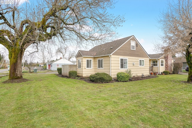 back of house featuring a lawn and roof with shingles