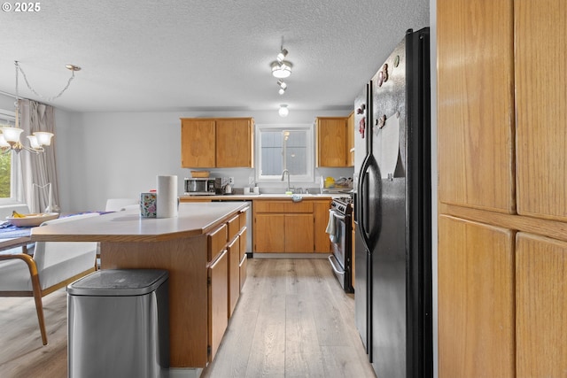 15302 NE 88th St, Vancouver, WA 98682 - kitchen with appliances with stainless steel finishes, light wood-type flooring, plenty of natural light, a kitchen island, and a textured ceiling