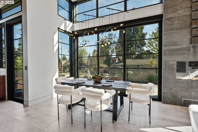 dining area with plenty of natural light, tile patterned flooring, visible vents, and a towering ceiling