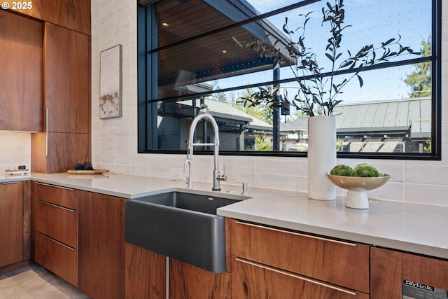 kitchen featuring light countertops, modern cabinets, a sink, and tasteful backsplash