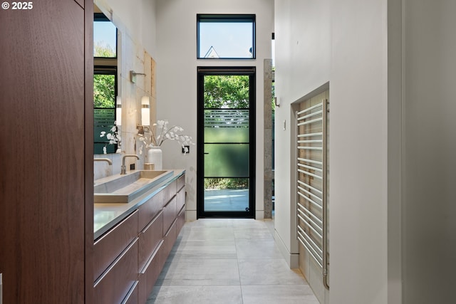 doorway featuring a sink, light tile patterned floors, a high ceiling, and radiator heating unit