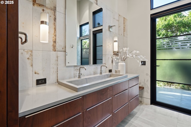 bathroom with vanity, decorative backsplash, and a healthy amount of sunlight