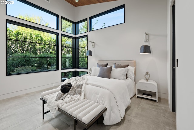 bedroom featuring high vaulted ceiling, multiple windows, and baseboards