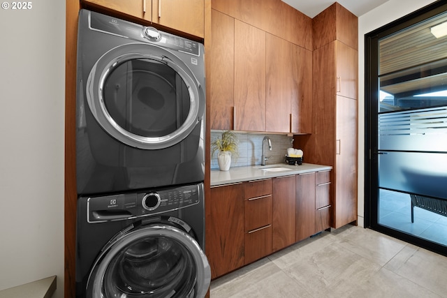 laundry area featuring a sink, stacked washer and dryer, and cabinet space