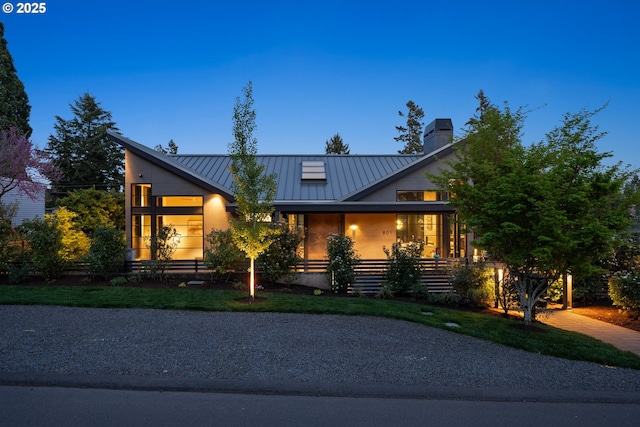 view of front facade featuring a standing seam roof, a chimney, a porch, and metal roof