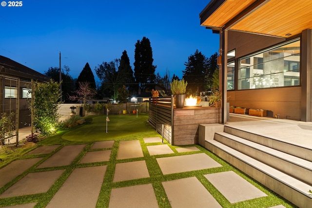 yard at twilight featuring a patio and fence