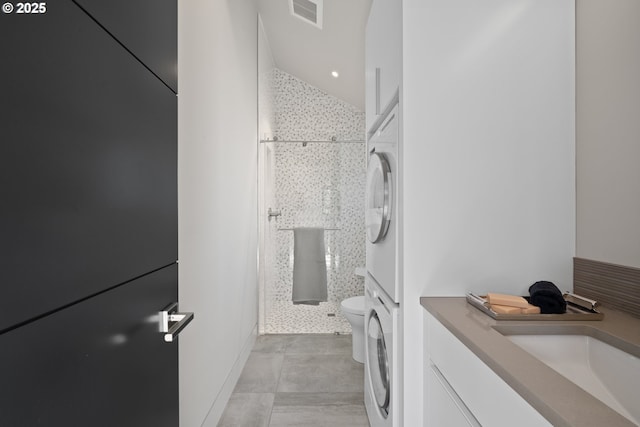 full bathroom featuring visible vents, stacked washer / drying machine, a shower stall, vanity, and toilet