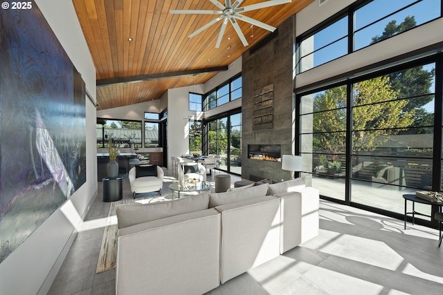 tiled living area with a tiled fireplace, a ceiling fan, high vaulted ceiling, and wooden ceiling