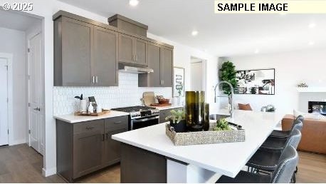 kitchen with stainless steel gas stove, a breakfast bar area, light hardwood / wood-style floors, and a kitchen island