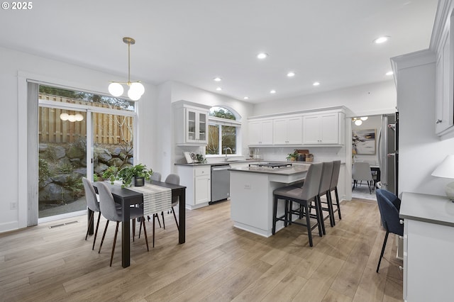 kitchen with stainless steel appliances, visible vents, white cabinets, a sink, and a kitchen bar