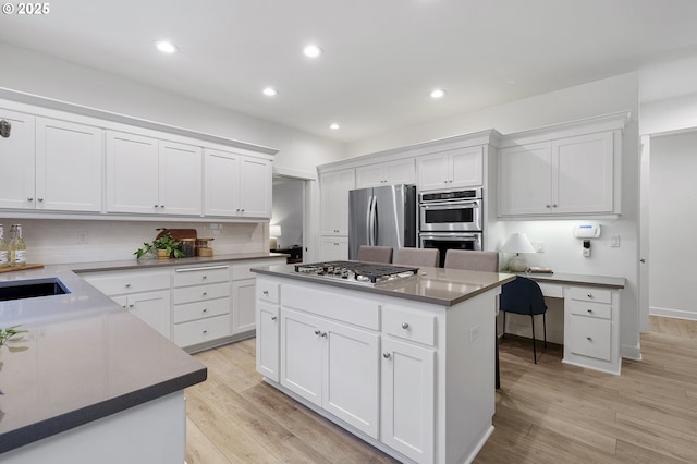 kitchen with a center island, stainless steel appliances, recessed lighting, light wood-style flooring, and white cabinets