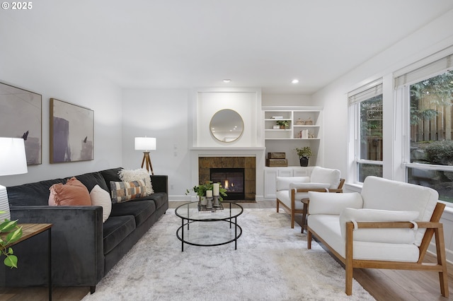 living area with baseboards, a tile fireplace, wood finished floors, and recessed lighting