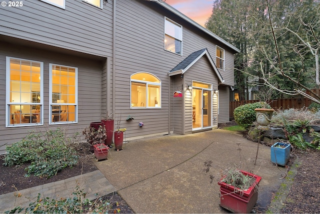 back of property at dusk featuring a patio area and fence