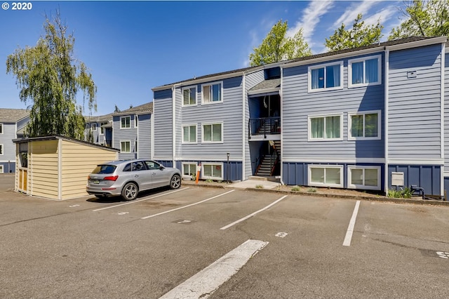 view of property featuring stairs and uncovered parking